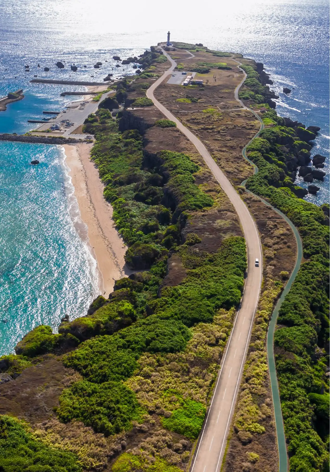 画像:海に囲まれた陸地で灯台へと続く道路を上空から撮影した様子